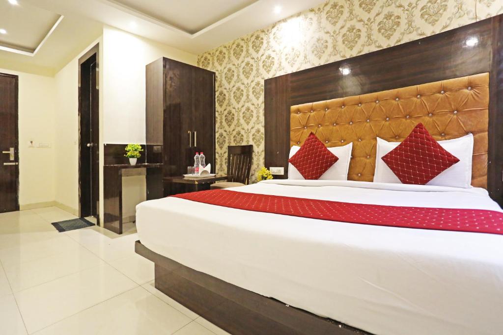 a bedroom with a large white bed with red pillows at Iconic Inn Near Delhi IGI Airport in New Delhi