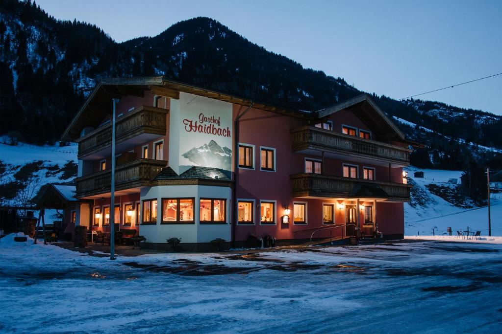 un grand bâtiment avec un panneau dans la neige dans l'établissement Gasthof Haidbach, à Mittersill