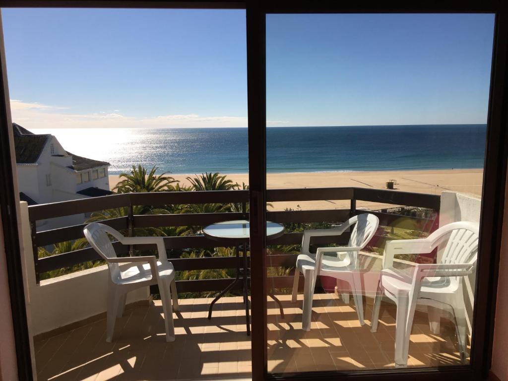 un balcón con sillas y una mesa y la playa en Appartement, praia da rocha, PORTIMAO, en Portimão