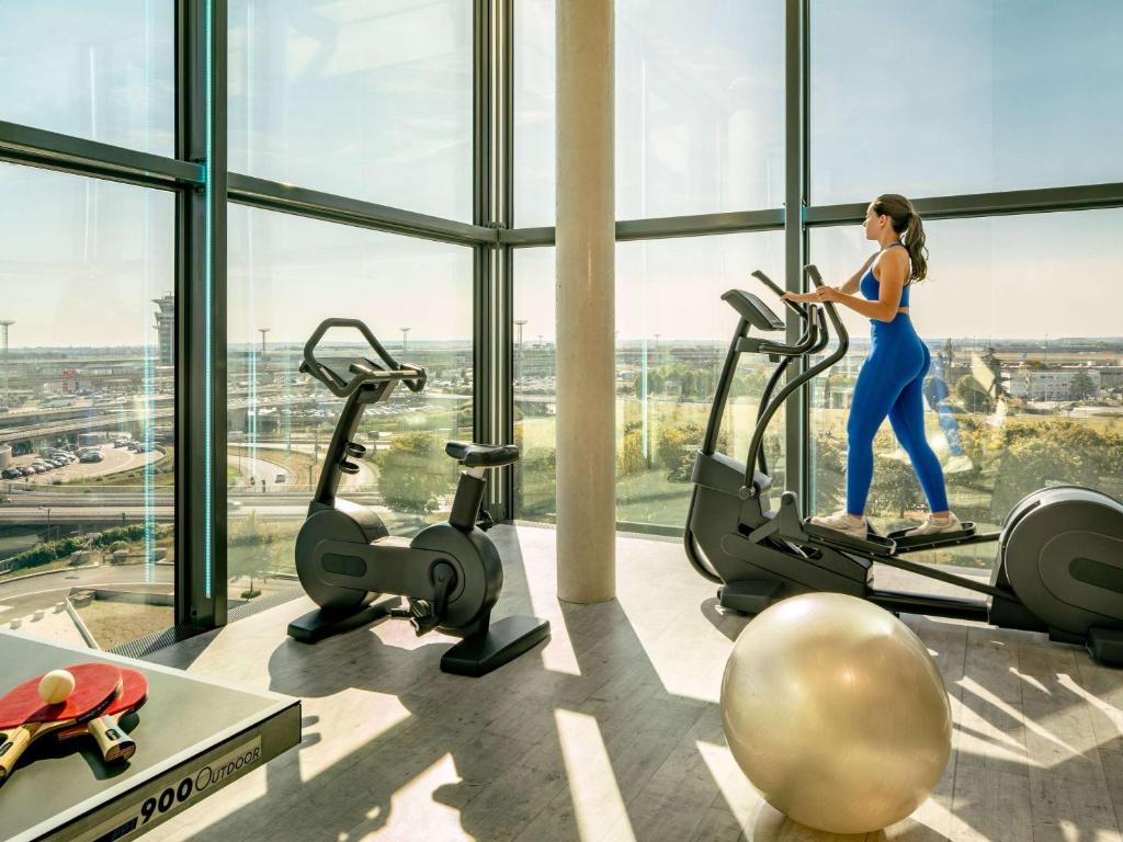 Una donna che corre su un tapis roulant in palestra di Novotel Paris Coeur d'Orly Airport a Orly