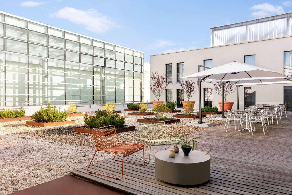 een patio met stoelen en tafels en een gebouw bij Vienna House Easy by Wyndham Stuttgart in Stuttgart