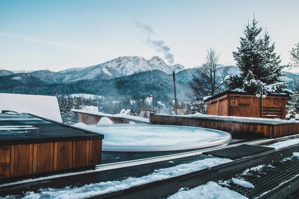 bañera de hidromasaje en un techo cubierto de nieve con montañas en Tatra Resort & SPA, en Kościelisko