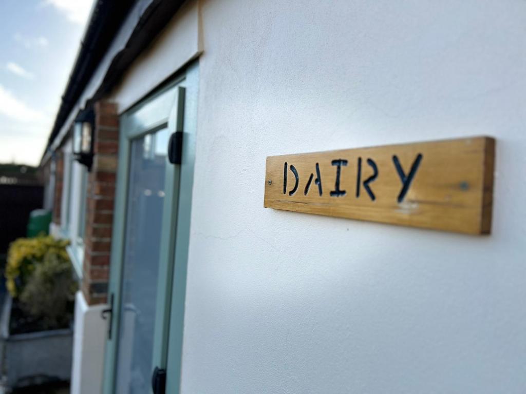 Un cartello che dice latticini sul lato di un edificio di The Dairy, Bramble Farm Cottages a Ferndown