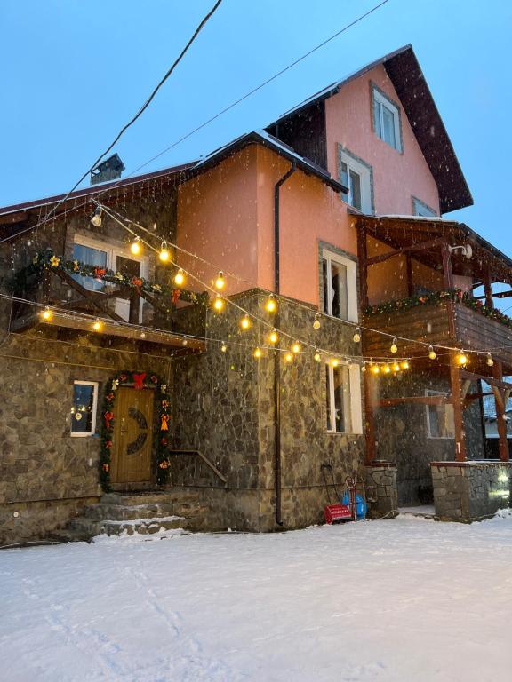 ein Gebäude mit Weihnachtslichtern im Schnee in der Unterkunft Садиба Рокса in Slawske