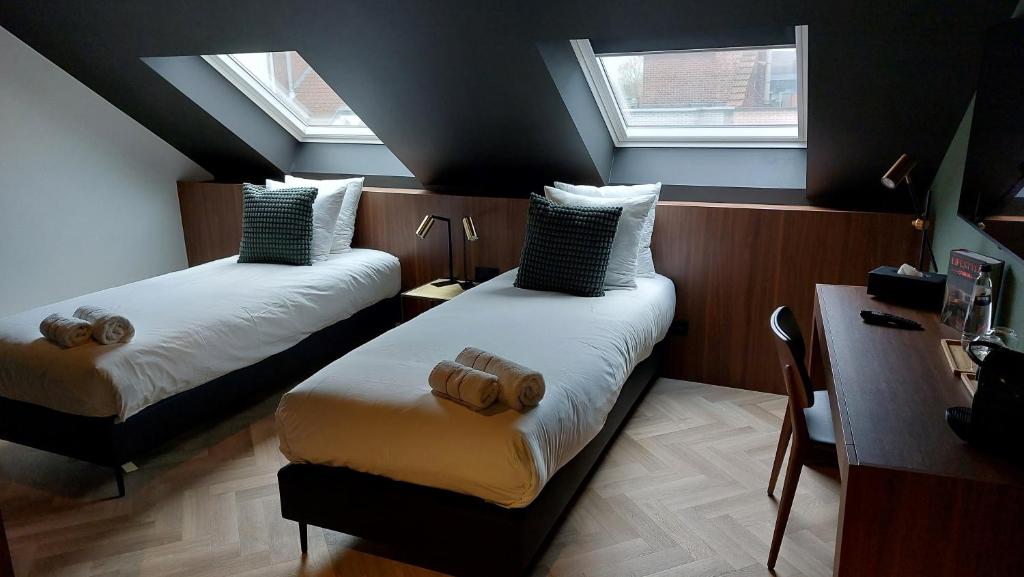 2 Betten in einem Zimmer mit 2 Fenstern in der Unterkunft Vinotel X in Tongeren