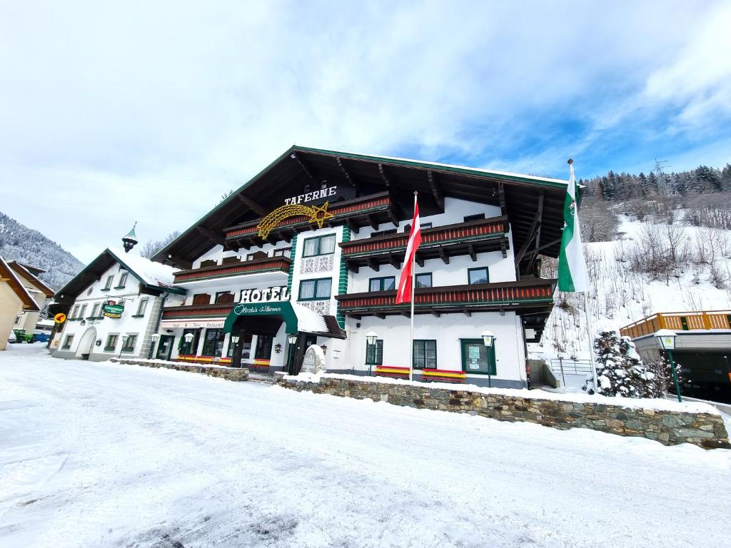 a large building with flags in the snow at Hotel & Gasthof Taferne in Schladming