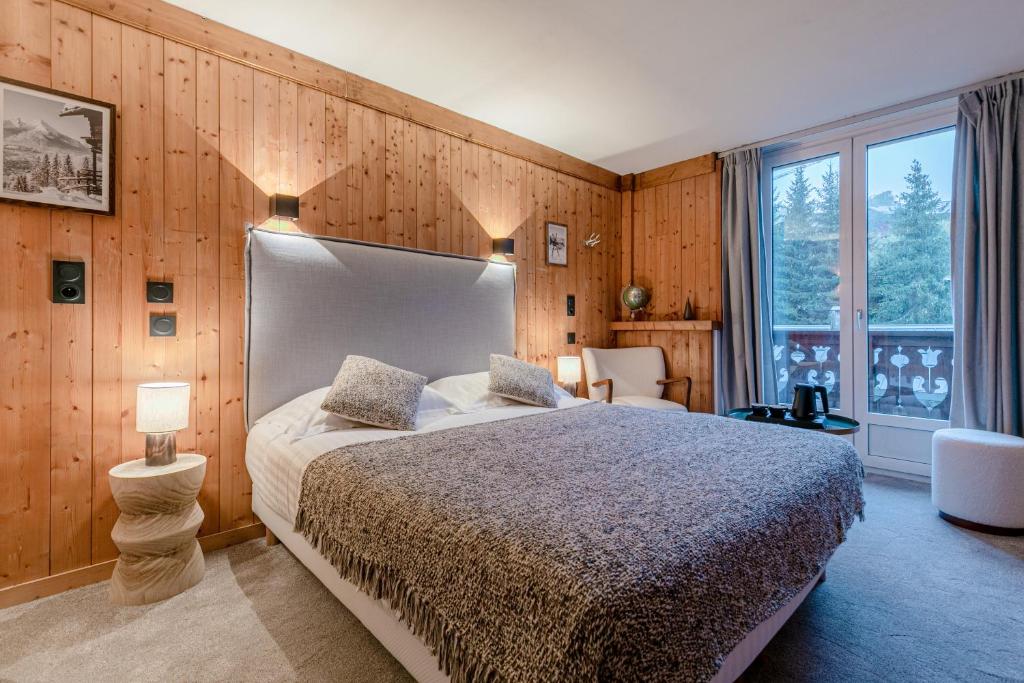 een slaapkamer met een groot bed en een groot raam bij Le Chalet d'Antoine - Centre de Megève in Megève