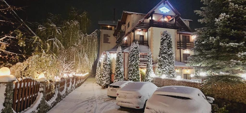 uma casa coberta de neve à noite com luzes em Hotel Bran Stoker em Bran