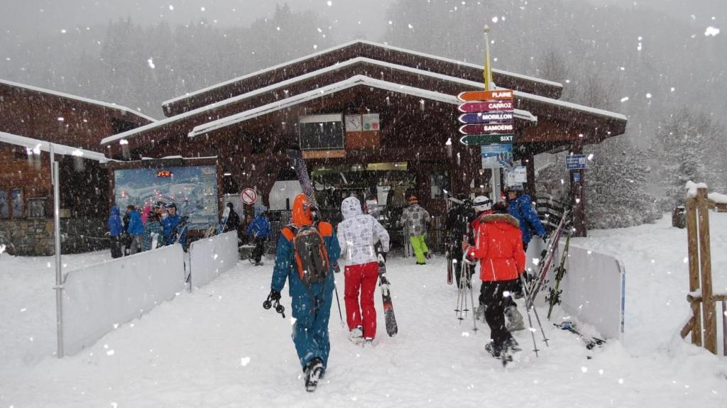 een groep mensen die in de sneeuw voor een gebouw lopen bij Charmant mobilhome à 2 pas remontés ski Samoëns in Samoëns