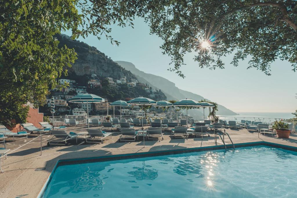 una piscina con sedie e ombrelloni di Hotel Poseidon a Positano