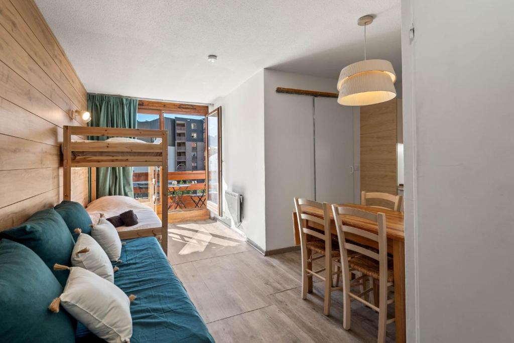 a living room with a blue couch and a table at Smartstay Altineige - Val Thorens in Val Thorens