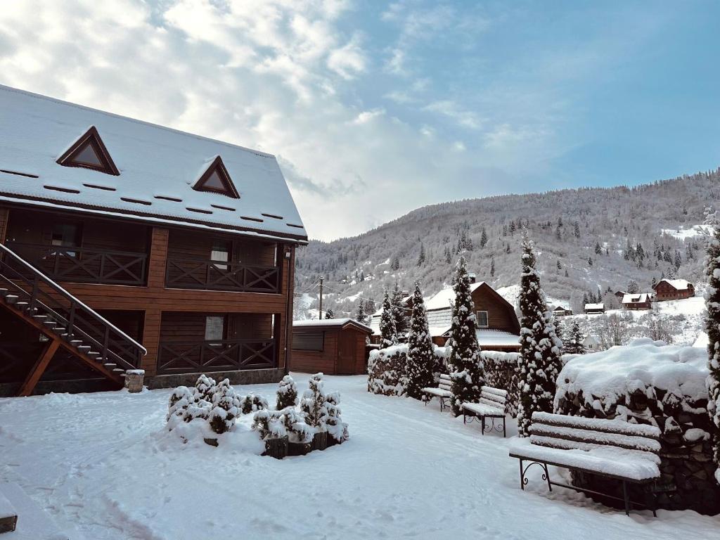 un edificio cubierto de nieve con un banco delante en Chalet Filvarok, en Slavske