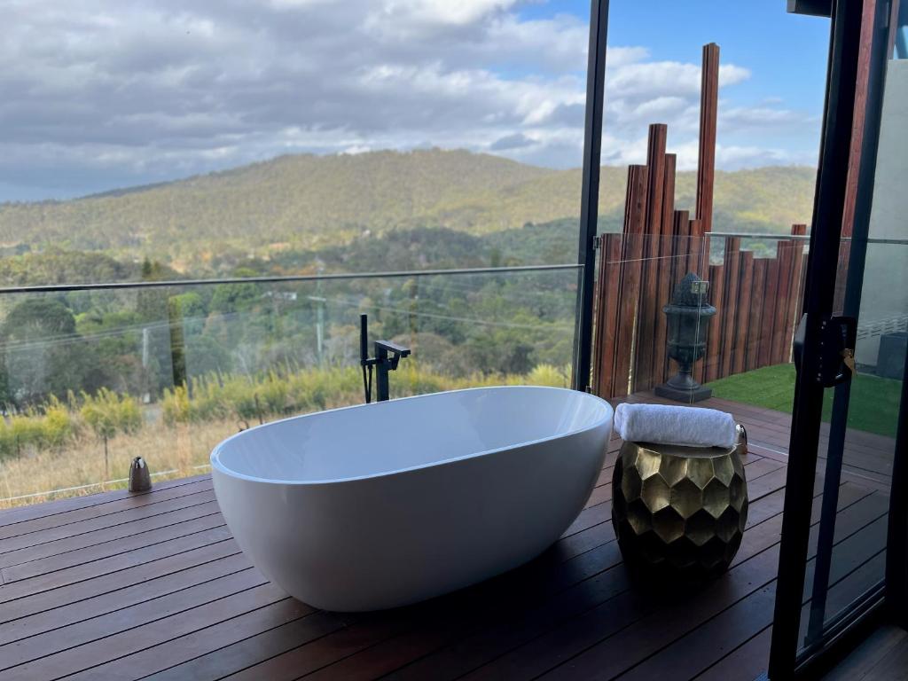 a white bath tub sitting on a deck with a window at On Eagle Wings Mountain Retreat & Spa in Neranwood