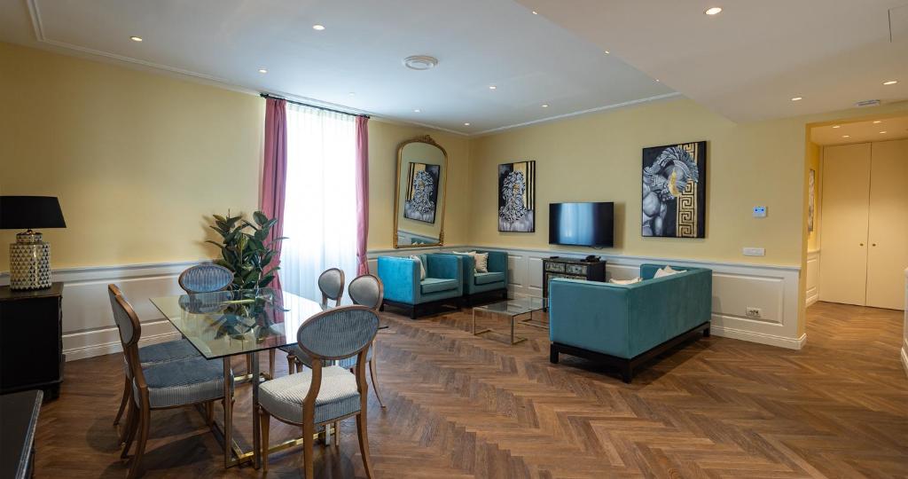 un soggiorno con tavolo, sedie e TV di Algilà Luxury Torrigiani Apartments a Firenze