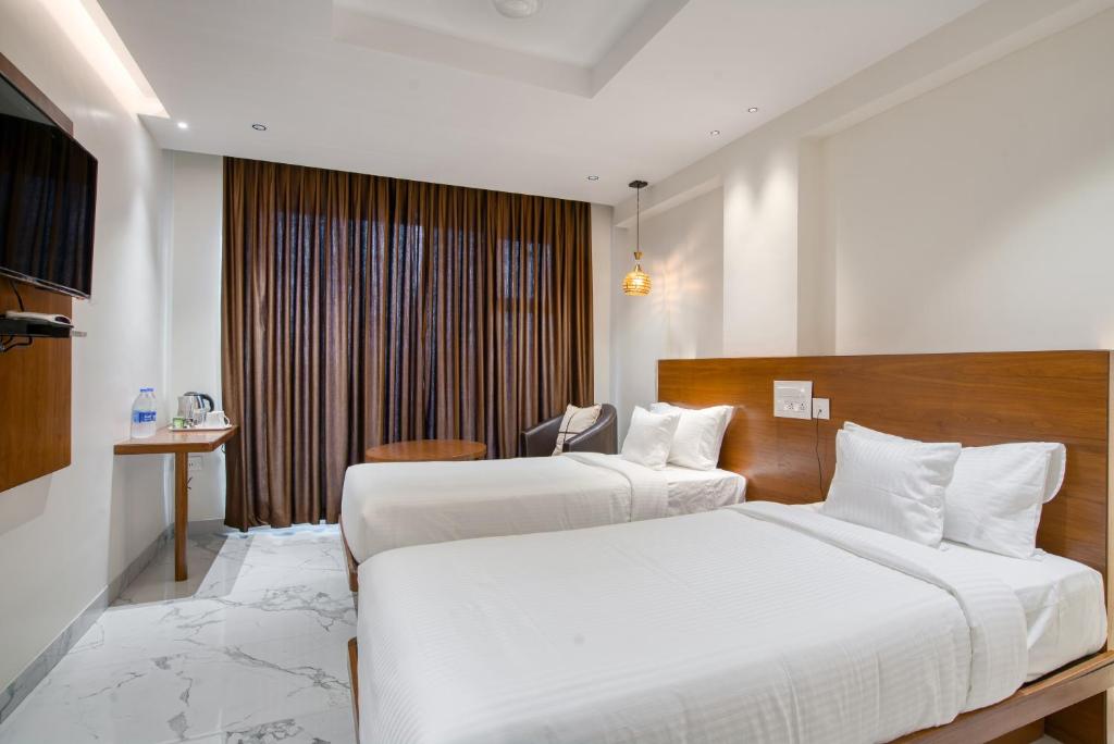 a hotel room with two beds and a desk at Hotel Vilvah in Coimbatore