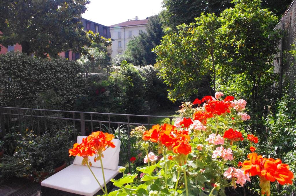 a bench in a garden with red flowers at Teodora B&B in Milan