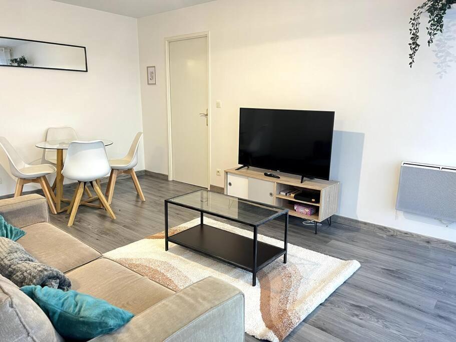 een woonkamer met een bank, een tv en een tafel bij Cocon Eudenia - accès direct PARIS - 2 MIN RER - PARKING GRATUIT in Cergy