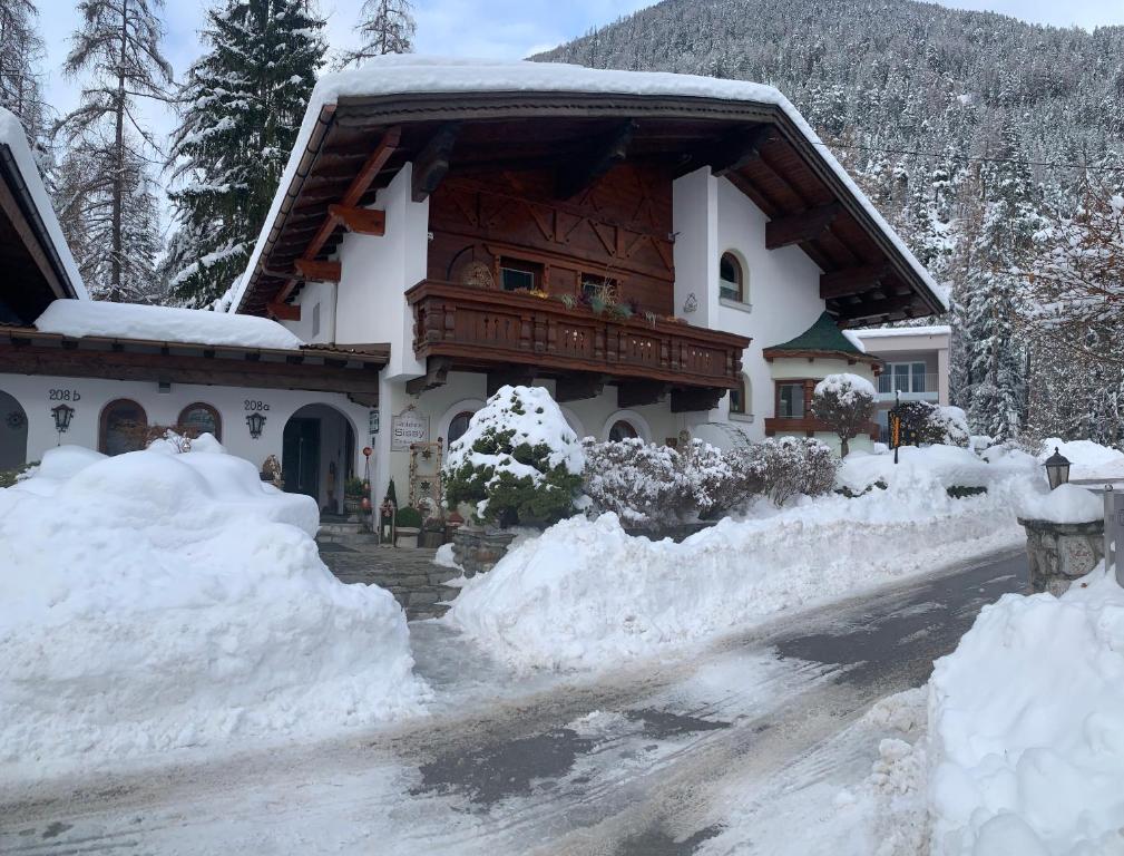 a house covered in snow on a street at Gästehaus Sissy in Längenfeld