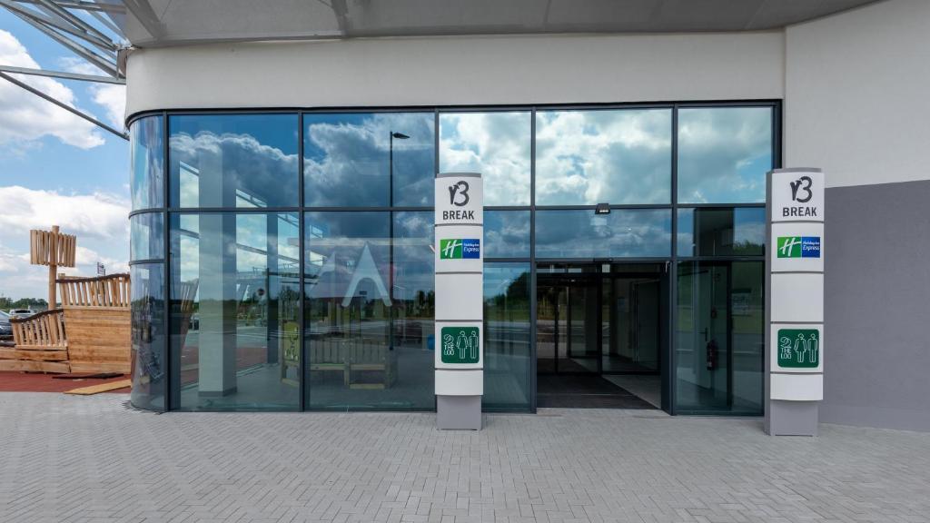 een groot glazen gebouw met een bord ervoor bij Holiday Inn Express - Hamburg South A7-AS42, an IHG Hotel in Egestorf