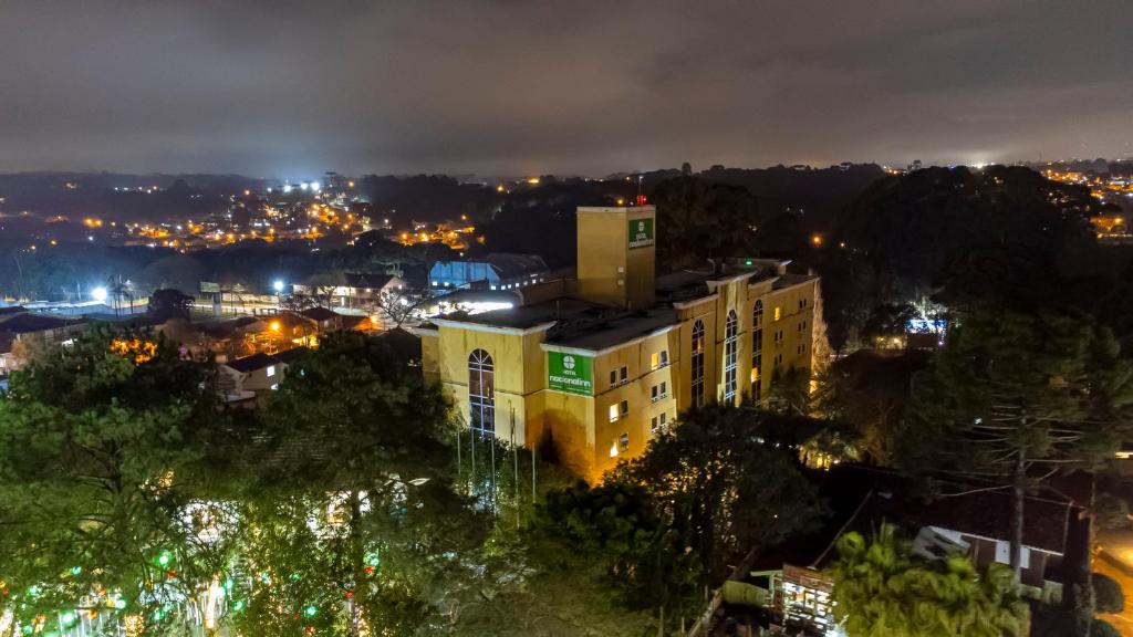 a city at night with a yellow building at Hotel Nacional Inn Curitiba Santa Felicidade in Curitiba