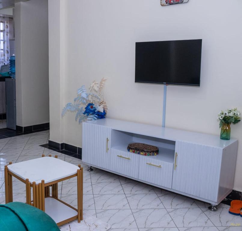 um centro de entretenimento branco com uma televisão de ecrã plano na parede em Tiny Haven executive one bedroom with Private Balcony em Nanyuki