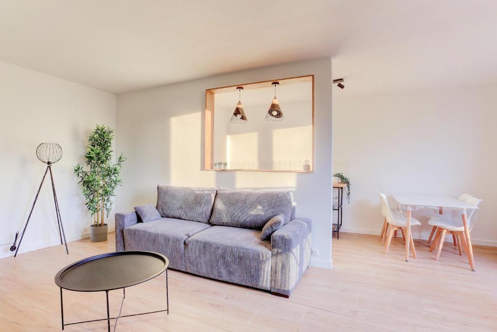 a living room with a couch and a table at Le Petit Nid - Apt Lumineux en Hypercentre in Montigny-le-Bretonneux