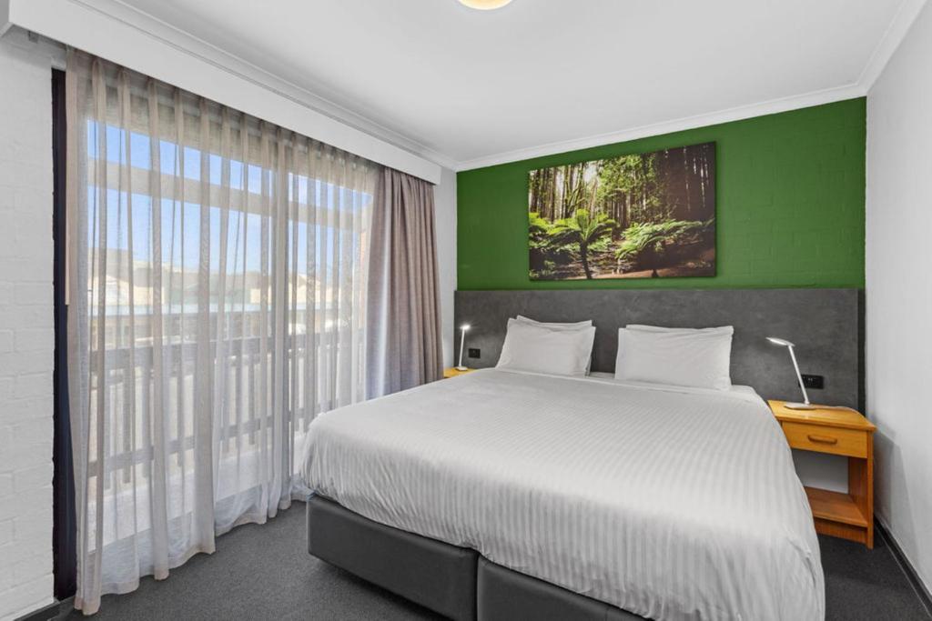 ein Schlafzimmer mit einem großen Bett und einer grünen Wand in der Unterkunft Apollo Bay Motel & Apartments, BW Signature Collection in Apollo Bay