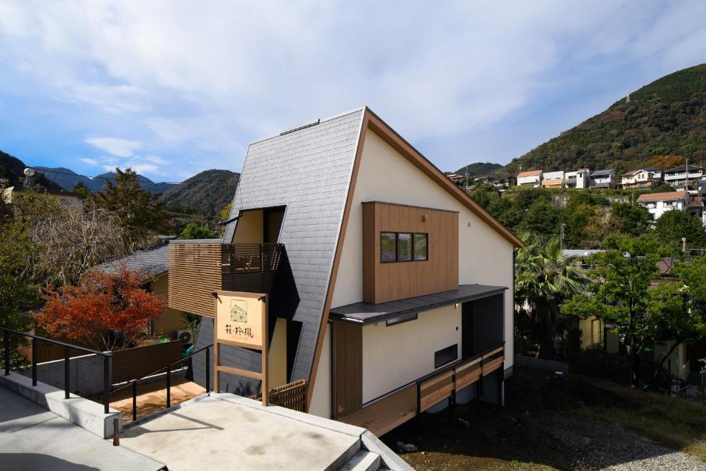 une petite maison sur une colline avec des montagnes en arrière-plan dans l'établissement HAKO REIRO 箱・玲瓏, à Hakone