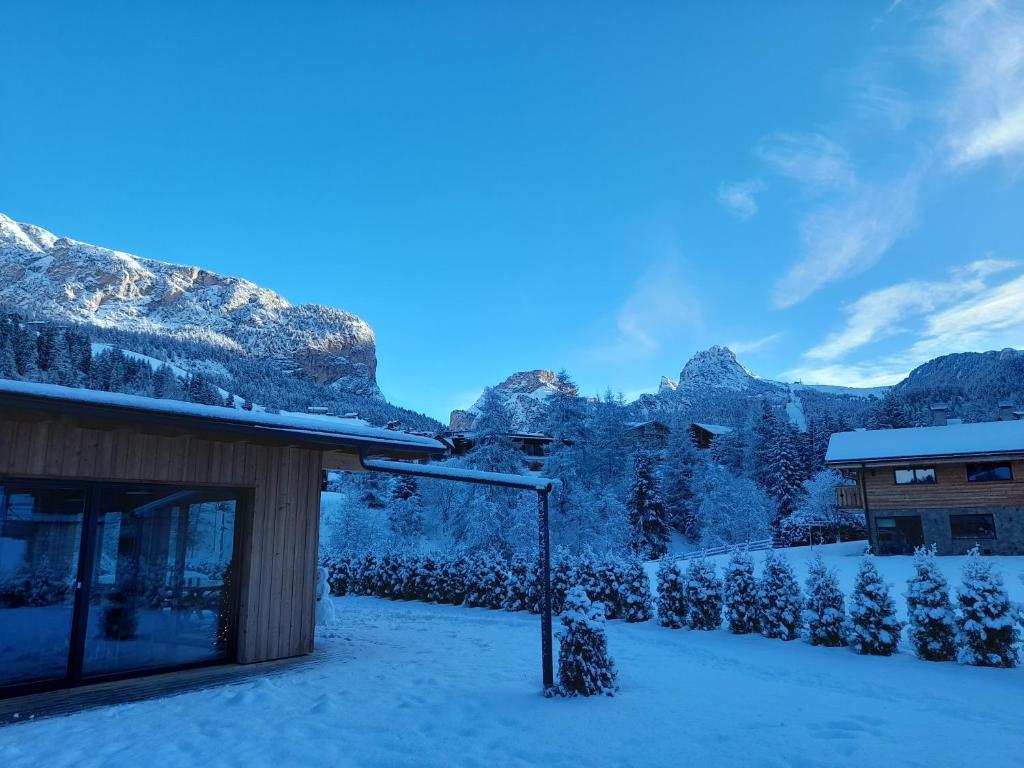 budynek pokryty śniegiem z górami w tle w obiekcie Chalet Dumbria Dolomites w mieście Selva di Val Gardena