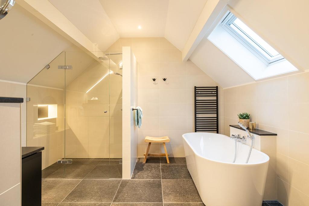 a bathroom with a large tub and a shower at Villa Zuiderduin in Zoutelande