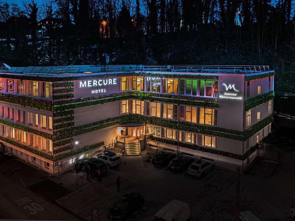 um grande edifício com uma placa à noite em Mercure Fribourg Centre Remparts em Fribourg