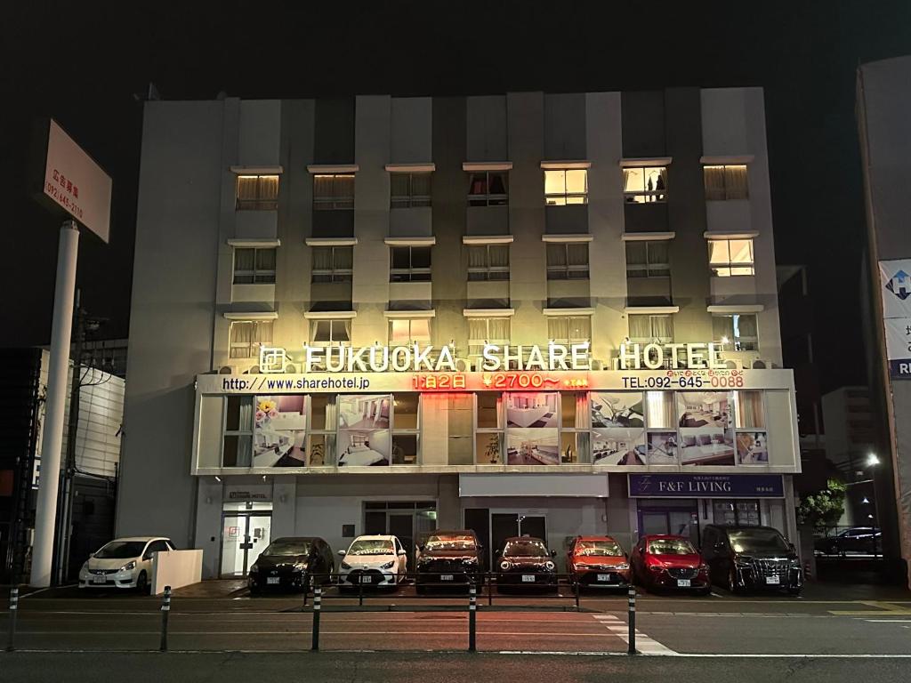 un edificio con coches aparcados delante de él por la noche en Fukuoka Share Hotel, en Fukuoka