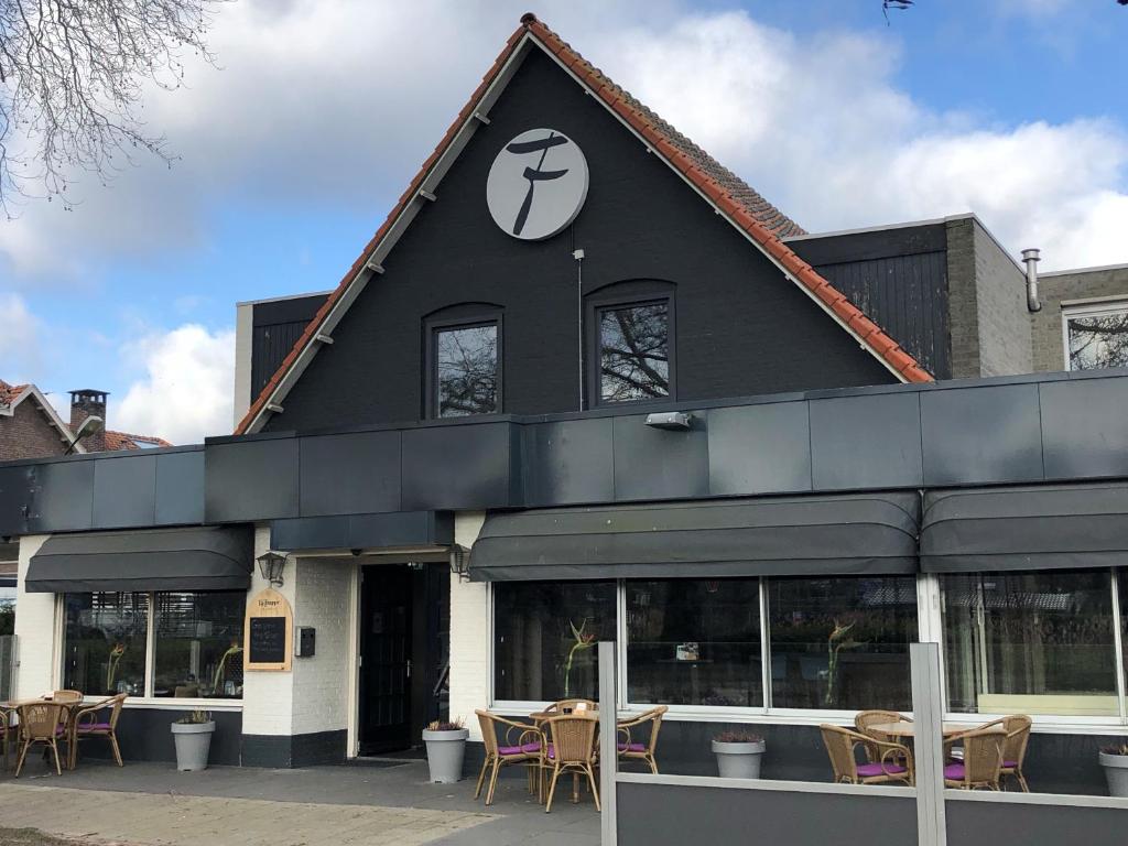 un bâtiment noir avec des tables et des chaises devant lui dans l'établissement Fletcher Hotel-Restaurant Waalwijk, à Waalwijk