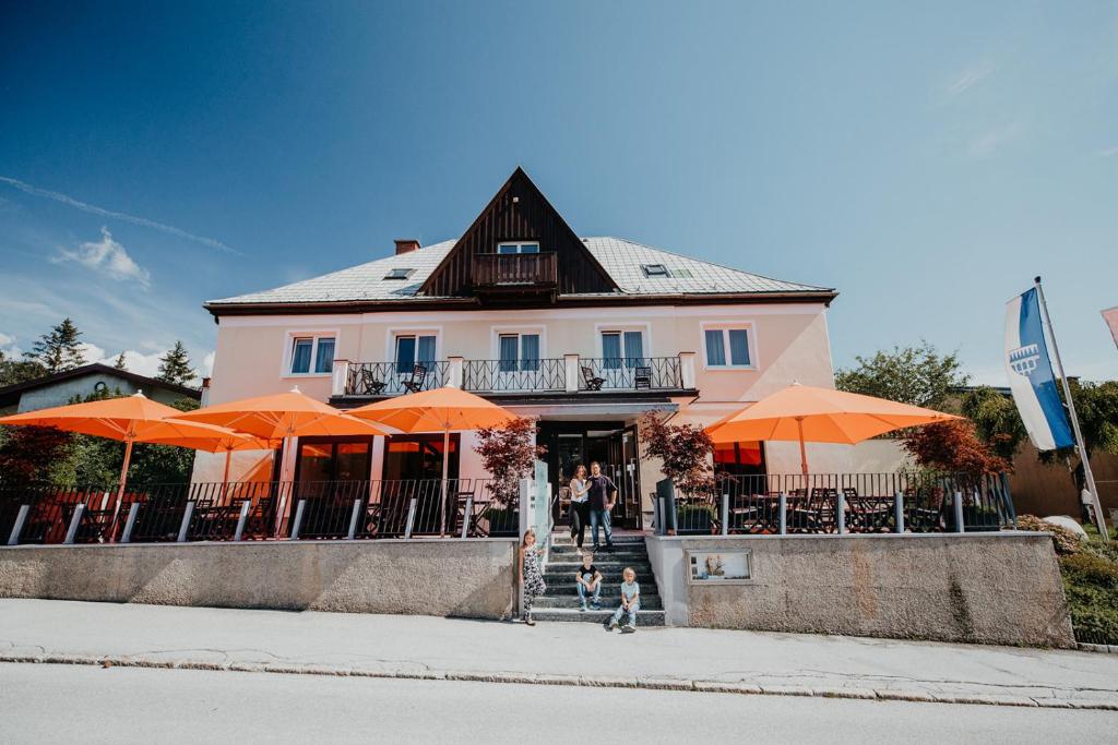 a pink building with orange umbrellas in front of it at Der Löffler am Semmering Bed&Breakfast in Semmering