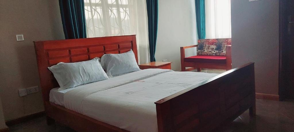 um quarto com uma cama grande e uma cadeira vermelha em SEED HOTEL em Entebbe