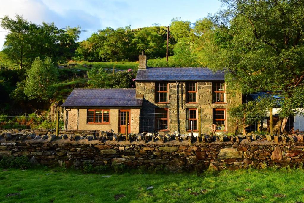 een stenen huis achter een stenen muur bij Terfyn Cottage in Dinorwic