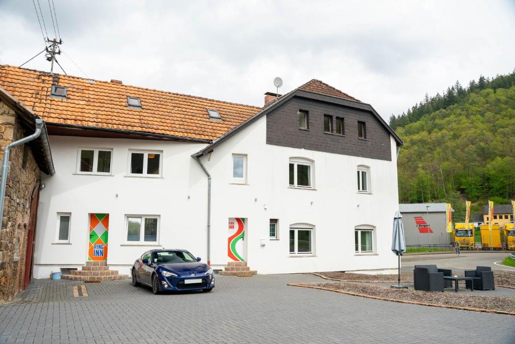 un coche aparcado frente a un edificio blanco en The Ring Inn, en Adenau