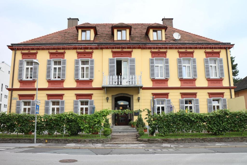 une maison jaune et rouge avec des escaliers devant elle dans l'établissement Privatpension Lang, à Leibnitz