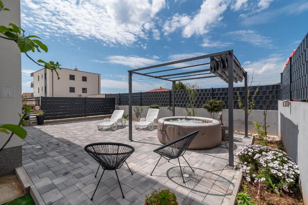 a patio with chairs and a hot tub on a patio at luxury apartment with garden jacuzzi in Trogir