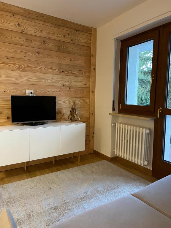 - un salon avec une télévision à écran plat sur un mur en bois dans l'établissement Condominio Le Grange - Casa E, à Sauze dʼOulx