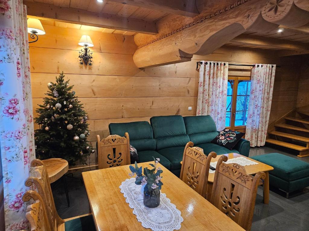 een woonkamer met een kerstboom en een tafel bij Domek Góralski Amelka in Poronin