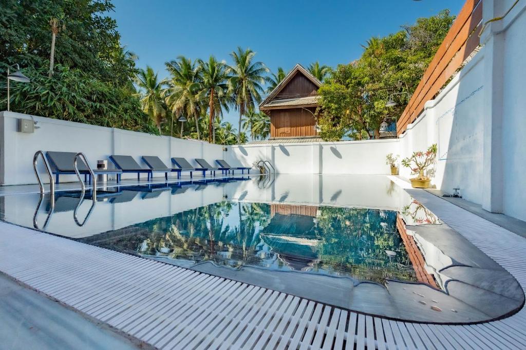 uma piscina com cadeiras ao lado de um edifício em LuangPrabang Center Hotel em Luang Prabang