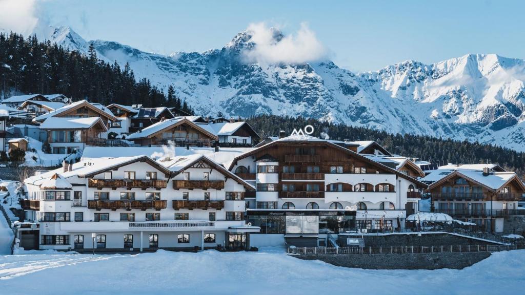 un hôtel dans la neige avec des montagnes en arrière-plan dans l'établissement Mountains Hotel, à Seefeld in Tirol