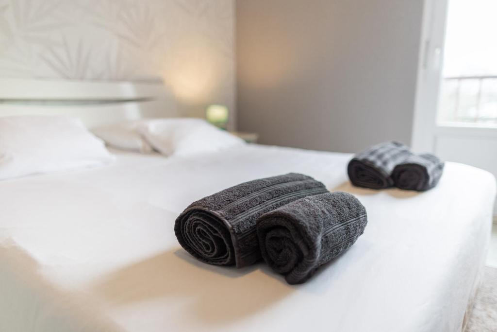 two rolls of towels sitting on a bed at Appartement Les Oiseaux in Thionville