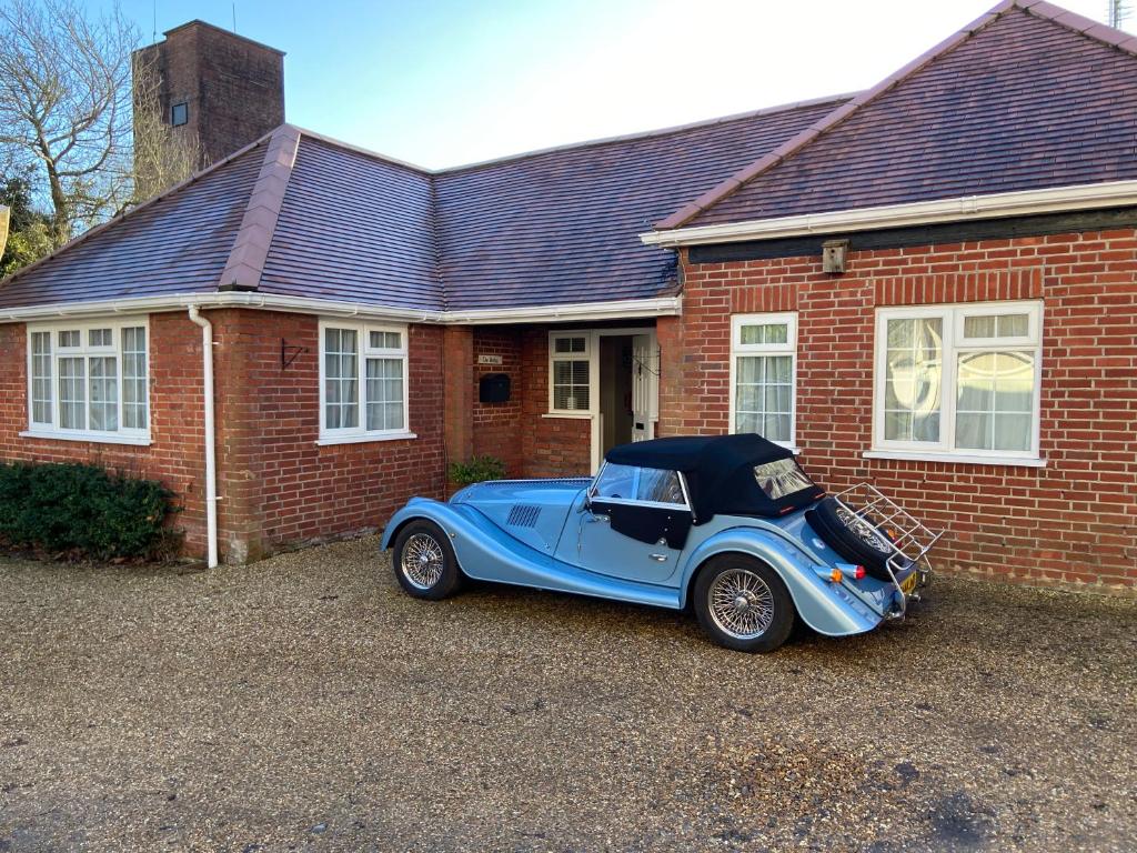 une voiture bleue garée devant une maison en briques dans l'établissement The Bothy, à Lyndhurst