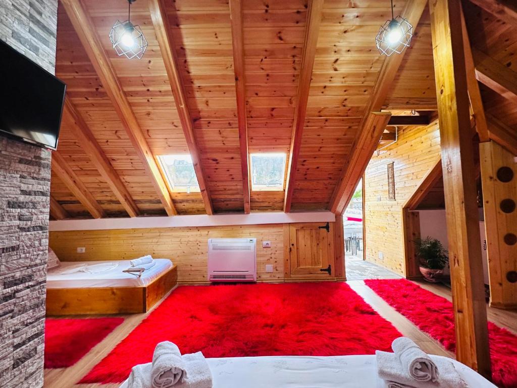 Cette chambre mansardée comprend 2 lits et un tapis rouge. dans l'établissement Kore Guest House, à Gjirokastër