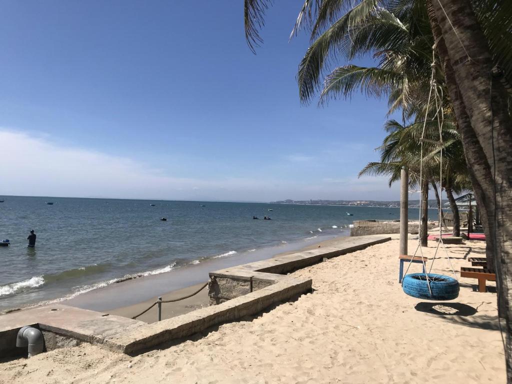 una spiaggia sabbiosa con palme e l'oceano di Nhat Quang Bungalow a Mui Ne