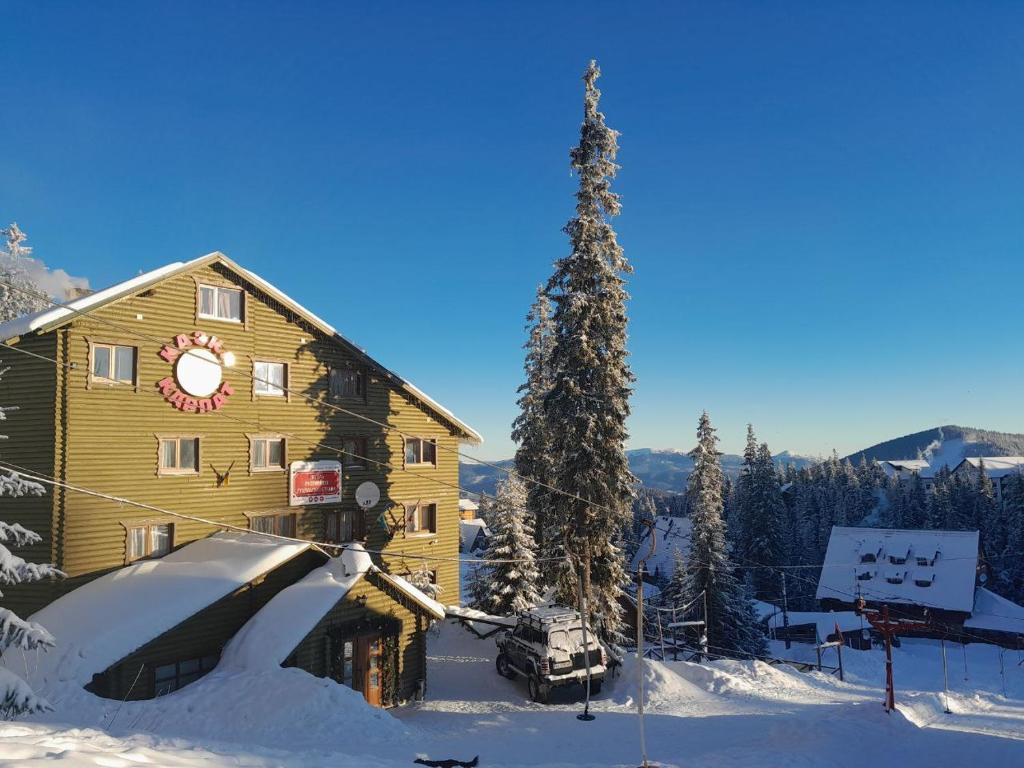 ein Gebäude im Schnee mit einem Auto daneben. in der Unterkunft Казка Карпат in Drahobrat