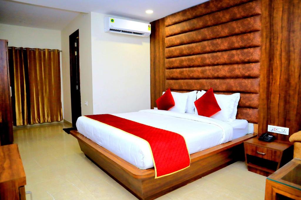 1 dormitorio con 1 cama blanca grande con almohadas rojas en Pineberry Hotels - Near Golden Temple, en Amritsar