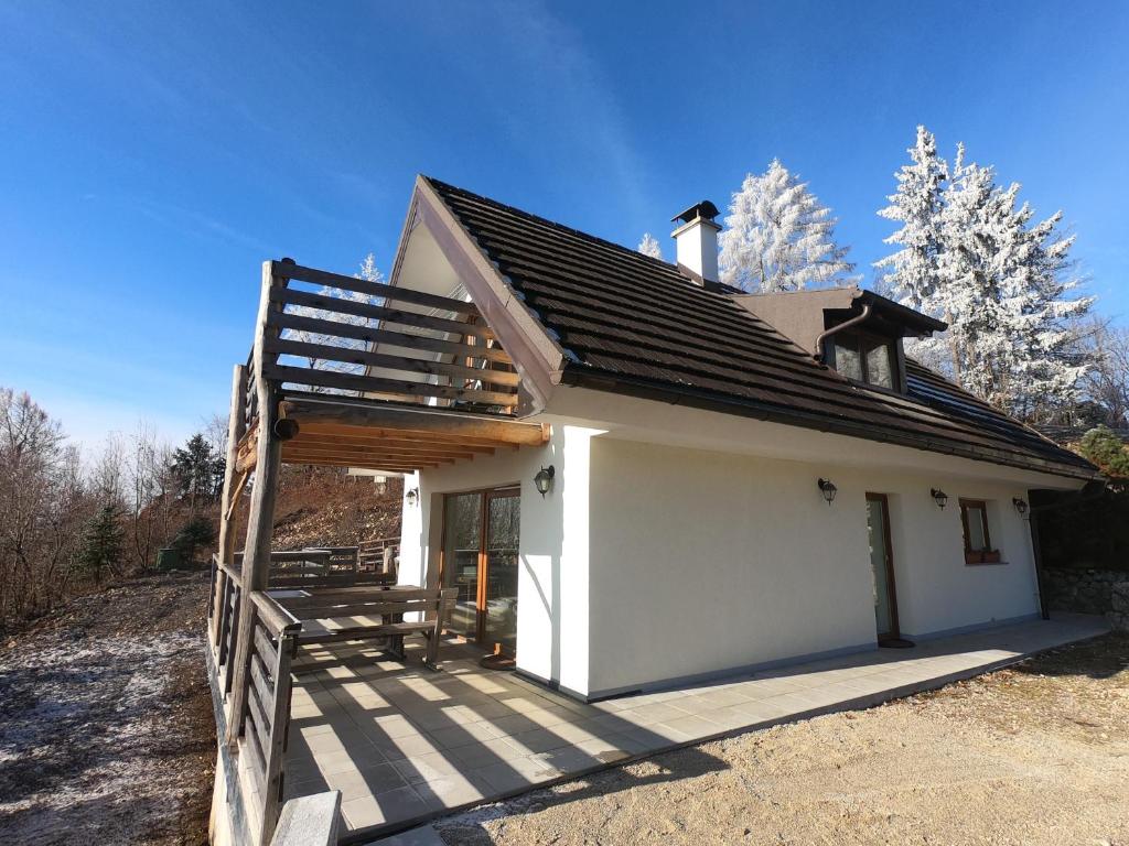 ein kleines weißes Haus mit einer Holzveranda in der Unterkunft Hiša v mesečini - Moonlight house in Cerklje na Gorenjskem